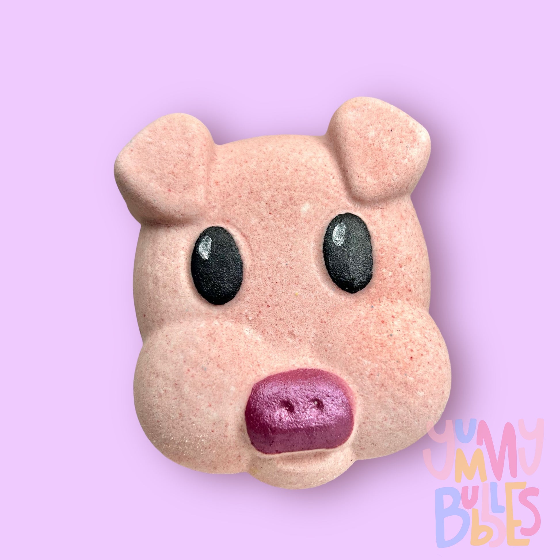 Pink pig head shaped bath bomb painted with dark pink, black, and white