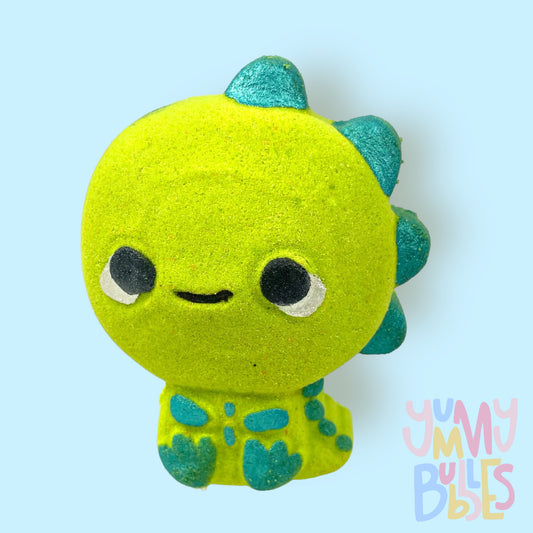 Green dinosaur shaped bath bomb painted with teal, white, and black.