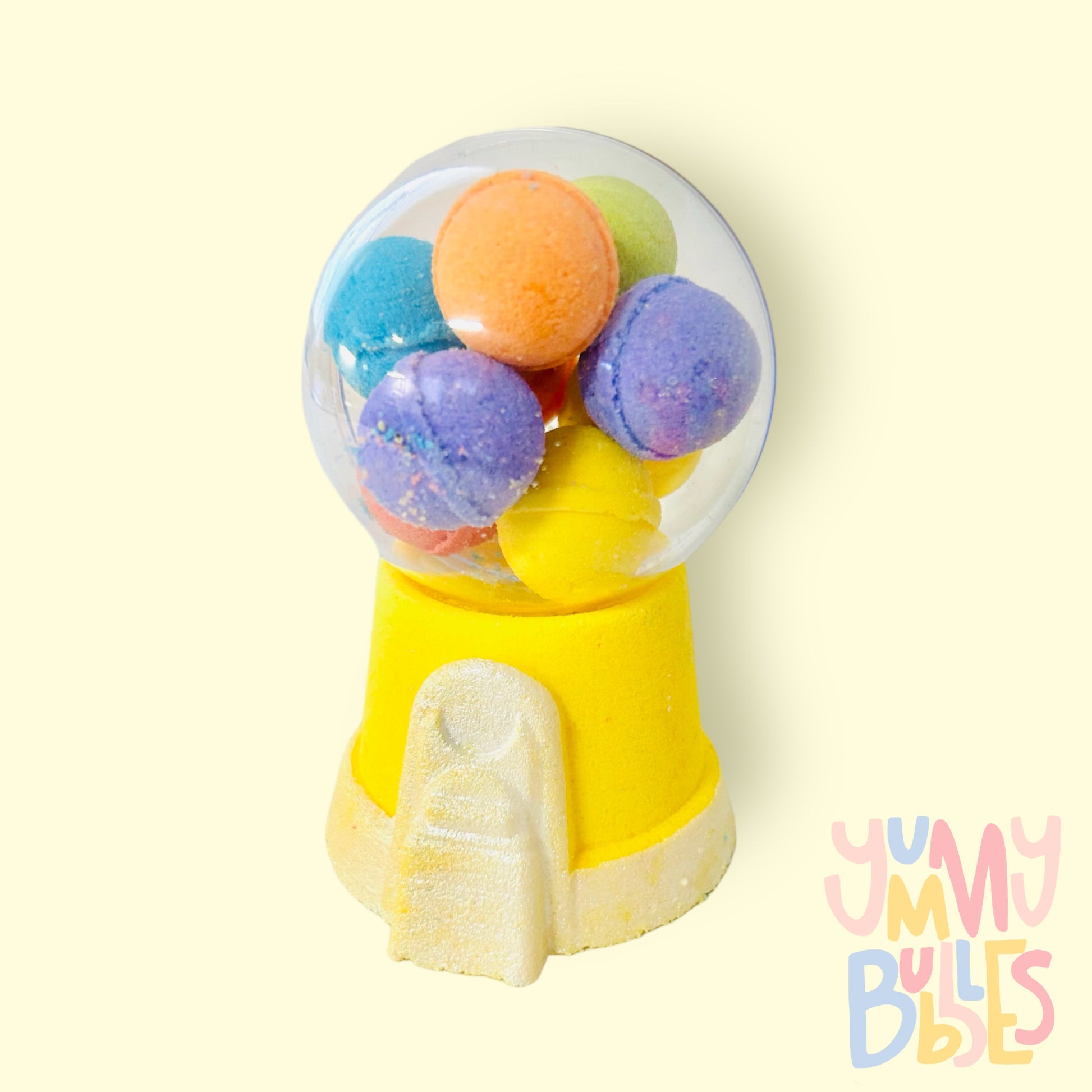 Yellow gumball machine bath bomb painted with white. Contains a plastic ball on top with a variety of different colored bath bomb gumballs.