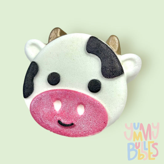 White cow shaped bath bomb painted with black, gold, and light pink