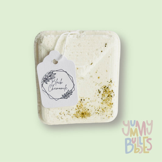 White tea bag shaped bath bomb with tea leaves embedded on top