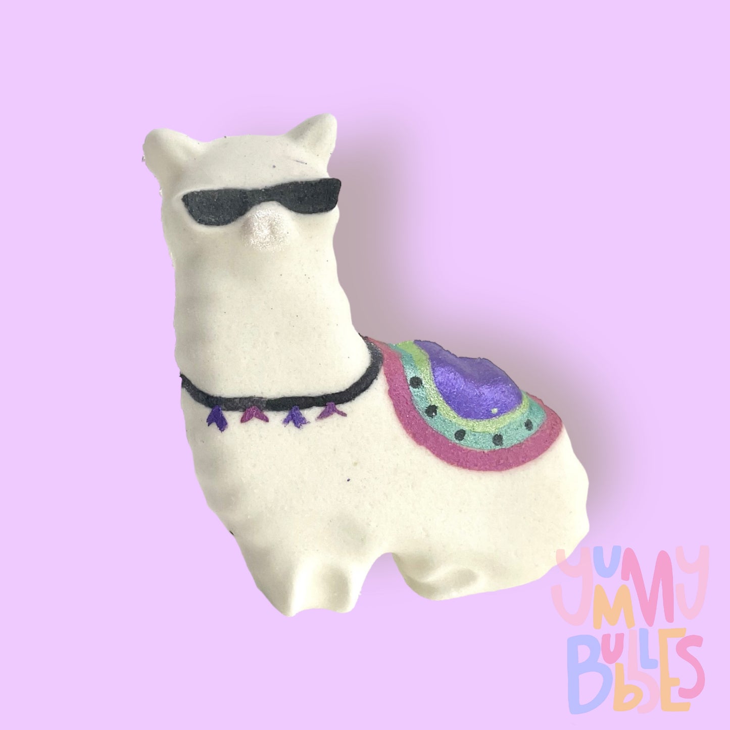 White llama shaped bath bomb with details painted in pink green, light green, purple, and black