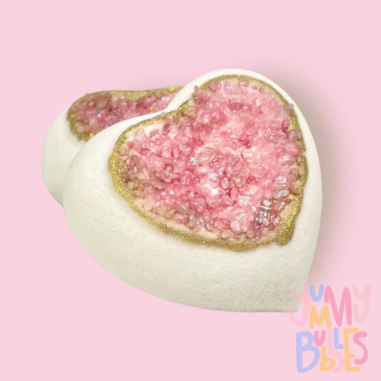 Heart shaped bath bomb with a geode like center, the geode being pink salts with a gold painted rim