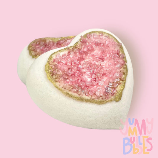 Heart shaped bath bomb with a geode like center, the geode being pink salts with a gold painted rim