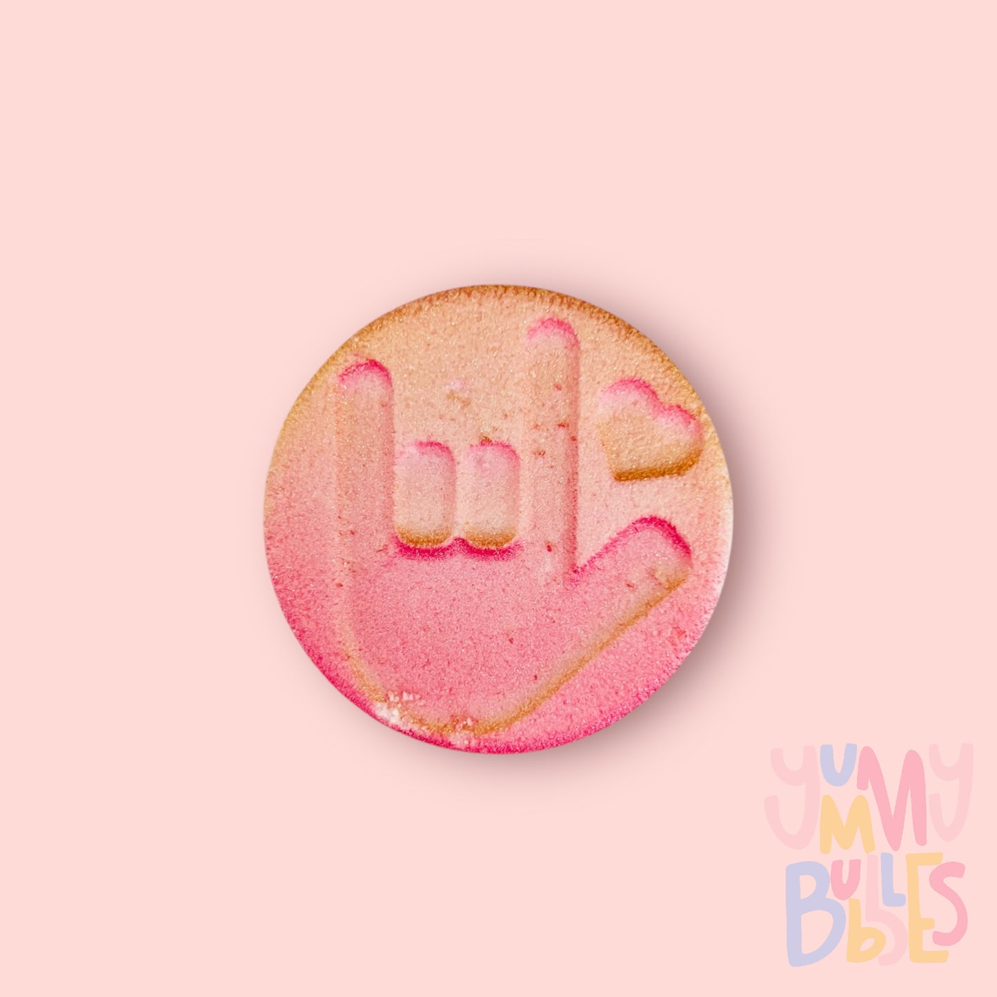 Round shaped bath bomb with  the Sign language for I love you. Painted with a pink to gold gradient