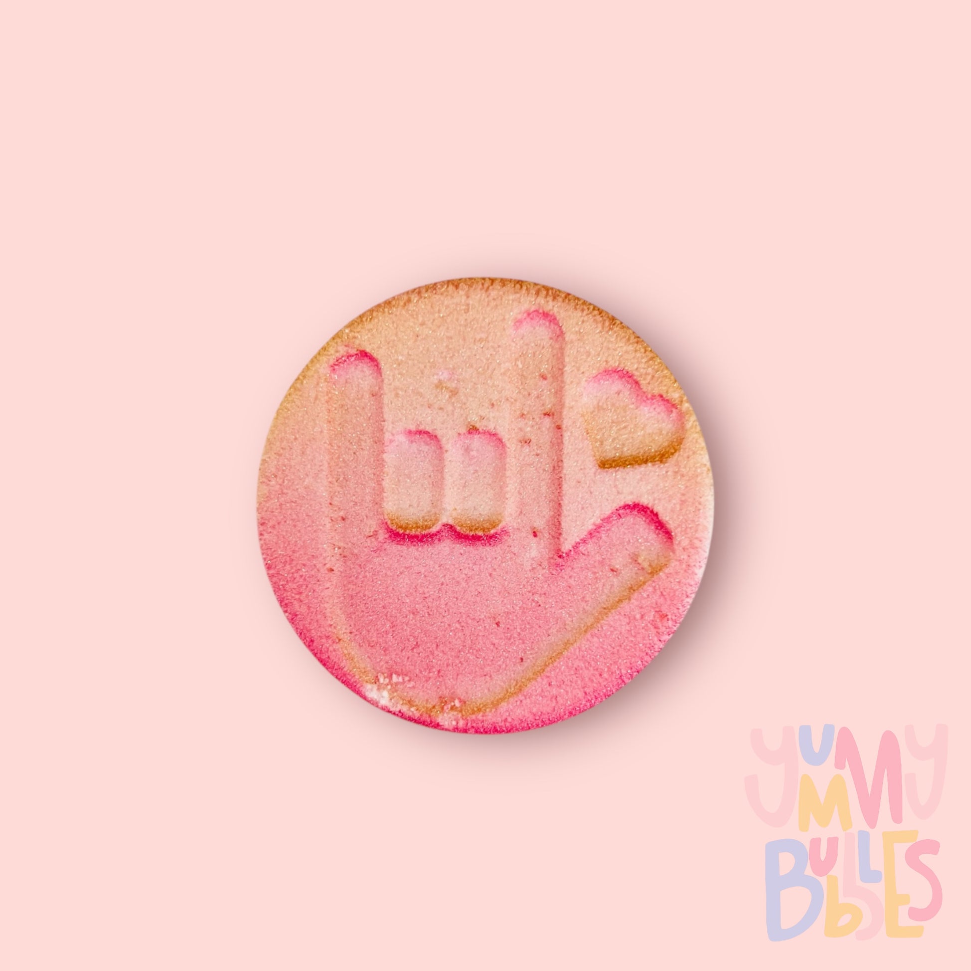 Round shaped bath bomb with  the Sign language for I love you. Painted with a pink to gold gradient