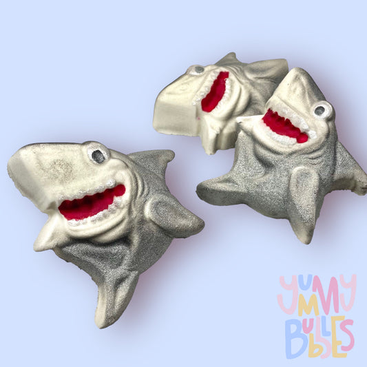 Shark shaped bath bomb painted with grey to highlight features. Mouth is painted with white and red and the eyes are painted with white and black