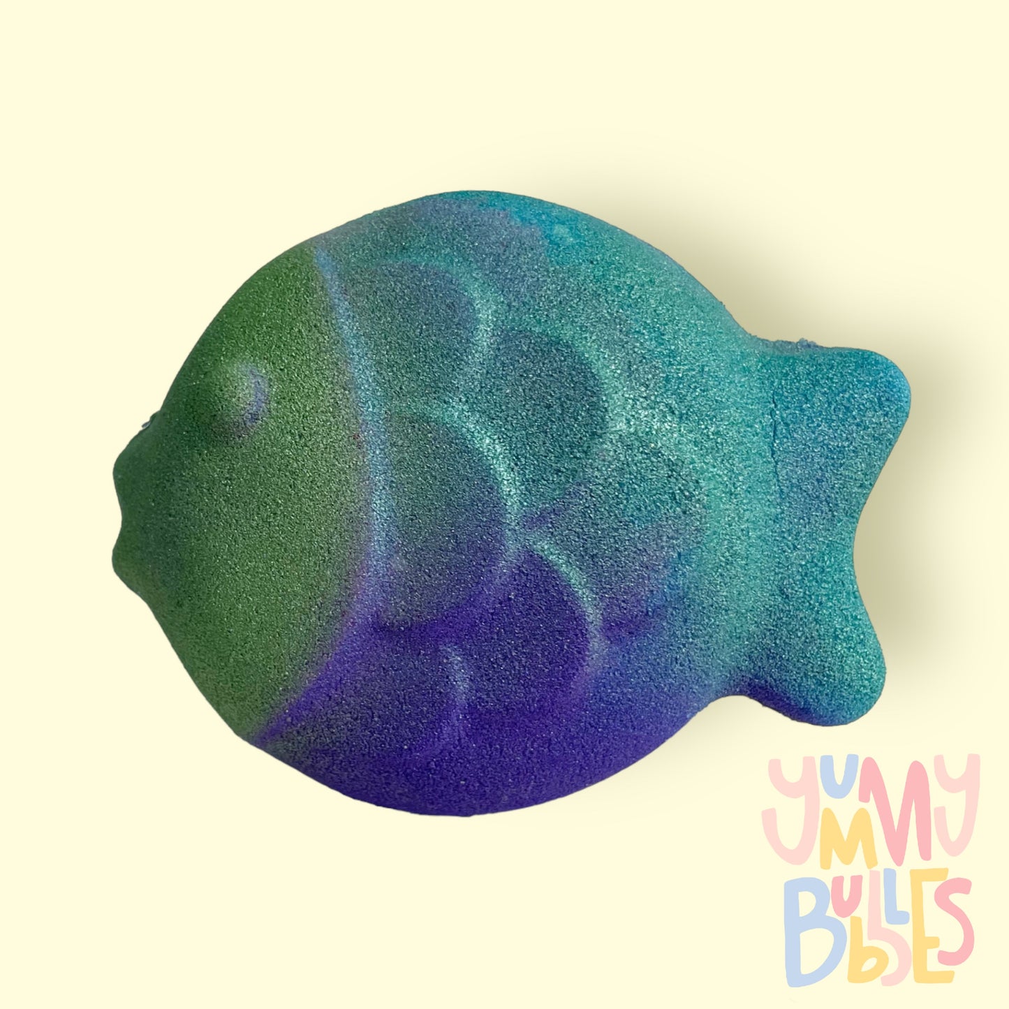 Fish shaped bath bomb with a blue, green, and purple airbrushed gradient painted on it