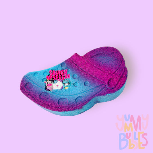 Blue croc shaped bath bomb highlighted with pink paint with a croc charm on top