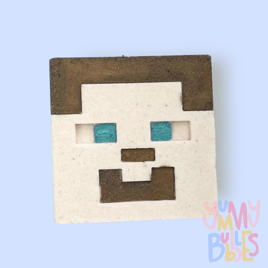 Square shaped bath bomb with Minecraft Steve's face, painted with brown and blue for facial details