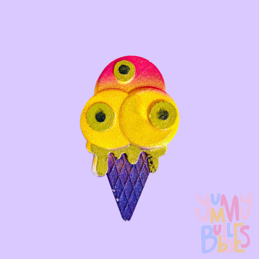 Ice cream shaped bath bomb with eye-balls, painted with pink, yellow, purple, and a greenish yellow.