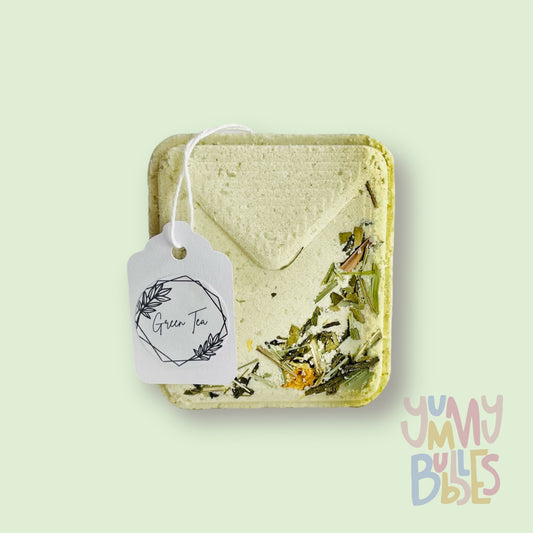 White tea bag shaped bath bomb with tea floral petals embedded on top