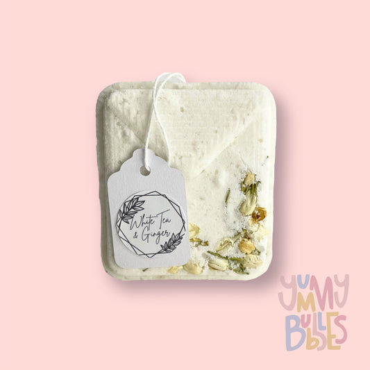 White tea bag shaped bath bomb with floral petals embedded on top