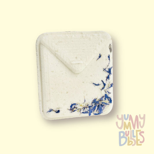 White tea bag shaped bath bomb with floral petals embedded on top