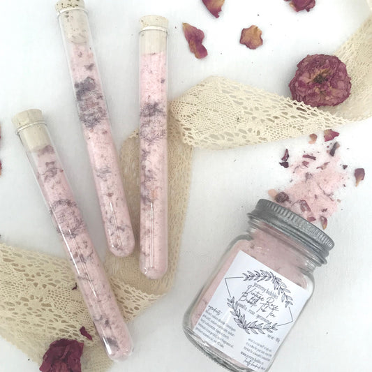 Pink bath bomb dust and rose petals mixed in clear test tubes or mason jars